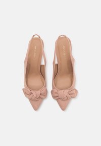Slingback høyhælte sko i myk rosa semsket skinn, med spiss tå og en dekorativ knyttet sløyfe foran.