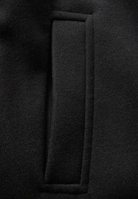 Tessuto felpato nero con un design di tasca rettangolare e elegante integrato nella superficie, che mette in risalto una texture liscia.