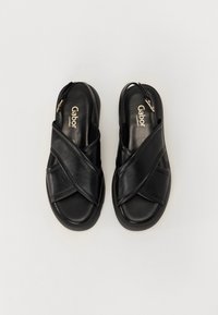 Mustat nahka-sandaalit ristikkäisellä designillä, avoimella kantapäällä ja säädettävällä hihnalla. Liukas pinta ja tasainen pohja mukavuutta varten. Gabor-logo näkyvissä.