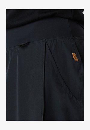 Mustat ulkoilushortsit, jotka on valmistettu kevyestä kankaasta; sisältää laskoksia, joustavan vyötärön ja pienen nahkalamppulogo-tarran.