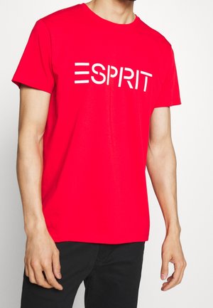 Punainen puuvillainen T-paita, jossa on valkoinen "ESPRIT" -logo rinnassa. Lyhyet hihat ja klassinen pyöreä kaula-aukko.