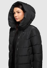 Zwarte donsjack met een grote, gestructureerde capuchon, een ritssluiting aan de voorkant en zijzakken. Kenmerkt zich door een doorgestikte structuur en een glad, glanzend materiaal.