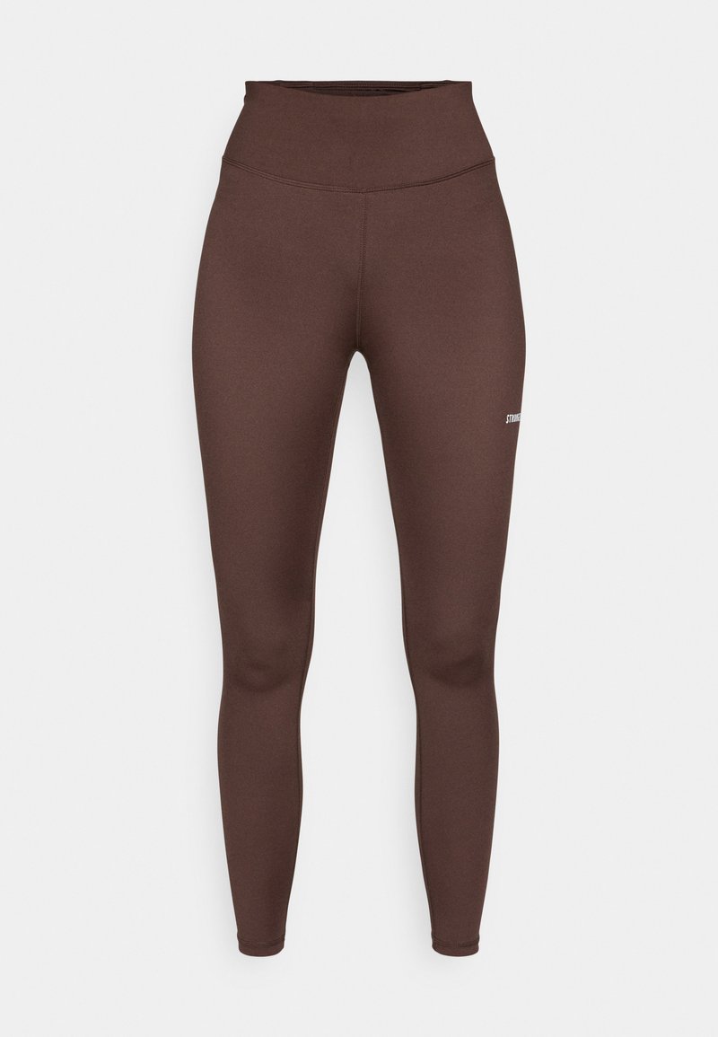 Bruine high-waisted leggings, gemaakt van rekbare stof. Harde textuur met platte naden en een klein logo aan de zijkant. Strakke pasvorm.