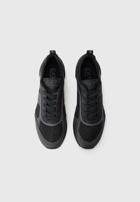 Black athletic shoes featuring a mesh upper, smooth synthetic accents, and a textured sole. Laces and pull tab for easy wear.
