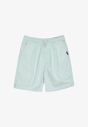 T-shirt en coton blanc avec un graphique coloré, associé à un short vert menthe. Des baskets noires et des chaussettes blanches complètent la tenue.