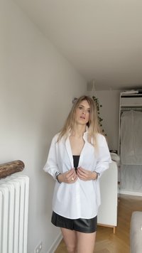Fehér, hosszú ujjú ing, texturált anyagból, fekete műselyem felsővel és bőrnadrággal párosítva. Egyszerű dizájn, felgörbített mandzsettákkal.