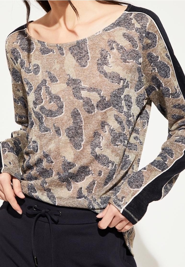 Langsleeve top met een beige en zwart dierenprintpatroon, met een zachte textuur en contrasterende zwarte mouwen met witte accenten.