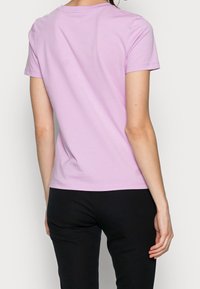 Kortärmad t-shirt i mjuk, pastelllila bomull. Standard rund halsringning, figursydd form, sömfri finish vid ärmar och nederkant.