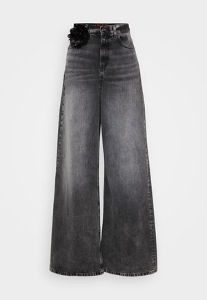 Vide benjeans i falmet svart denim, med høy midje og en dekorativ svart blomstermotiv på livet.