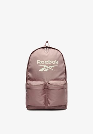 Mochila Reebok color malva claro con dos bolsillos frontales con cremallera y una asa superior, con el logo de Reebok en blanco en el panel frontal.
