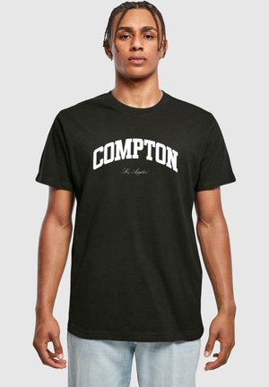 Sort bomulds T-shirt med fed hvid tekst "COMPTON" henover brystet og mindre "Los Angeles" nedenunder i kursiv skrifttype. Korte ærmer.