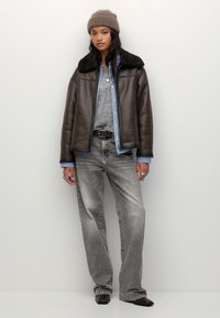 Smeđi kožni sako s umjetnim krznom, svijetla traper košulja, sivi džemper, široke sivoje traperice i smeđe čizme. Zabilježeni su jednostavni dodaci.