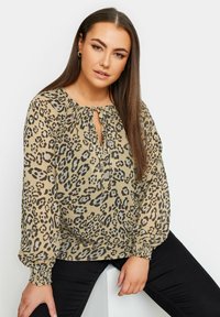 Blusa in fantasia leopardata in tessuto leggero; presenta un colletto arricciato con dettaglio a chiave e polsini elasticizzati. Toni marroni e beige.
