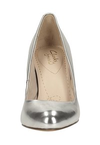 Zapato de tacón alto metálico plateado con puntera puntiaguda, textura suave y diseño minimalista. En su interior cuenta con una plantilla acolchada con el nombre de la marca.