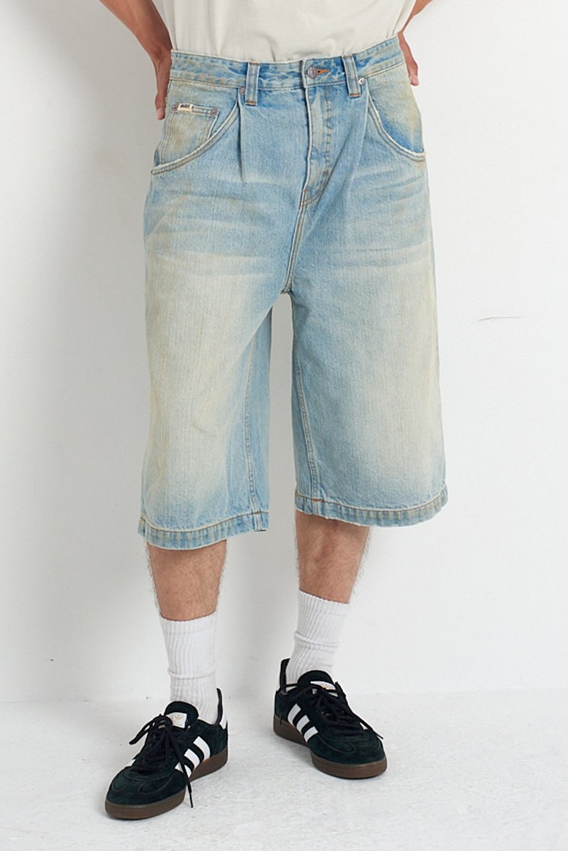Light blue denim shorts with a relaxed fit, featuring front pockets and a faded wash. Worn with black sneakers and white crew socks.