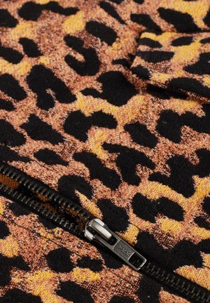 Zwart en oranje luipaardprint stof met zichtbare zwarte ritslus en tanden op een gestructureerd textieloppervlak.