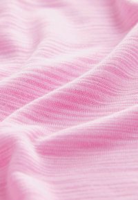 Hellrosa Stoff mit einer weichen, strukturierten Oberfläche, der subtile horizontale Streifen und sanfte Wellen aufweist, was auf Flexibilität und Fall hinweist.