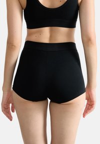 Svarta högmidjade shorts med en slät yta och elastisk midja, med en figurnära stil och rundade benöppningar.