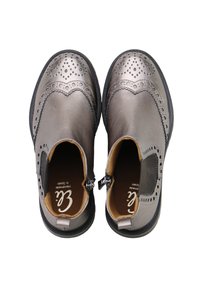 Botas de tobillo de cuero gris con detalle perforado, paneles laterales elásticos y suela de goma negra. El interior cuenta con un forro marrón.