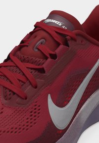 Μπορντό αθλητικό παπούτσι για τρέξιμο Nike με κόκκινες κορδόνια, αεριζόμενη επάνω ύφανση από δίχτυ, ασημένιο λογότυπο Swoosh και επένδυση στη γλώσσα με την ένδειξη "Pegasus 42".