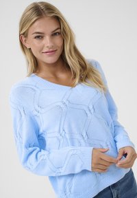Jasnoniebieski sweter z dzianiny z dekoltem w serek, teksturowanym wzorem i ściągaczami przy mankietach. Posiada otwartą konstrukcję splotu oraz luźny krój.