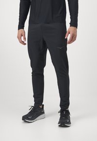 Pantaloni sport negri dintr-un material ușor, cu un design conic și logo reflectorizant. Asortați cu pantofi de alergare negri.