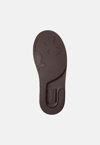 Suola di scarpa in gomma marrone caratterizzata da una superficie testurizzata e da un design a forma di gatto giocoso. Bordo curvo e leggera indentazione sul lato.