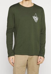 Langärmliges, olivgrünes T-Shirt aus Baumwolle mit einem weißen Berg-Design auf der Brust. Weicher Stoff und Rundhalsausschnitt.