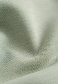 Helles grünes Gewebe mit einer glatten Textur und subtiler Rippstruktur, das ein weiches, dehnbares Material präsentiert, das für verschiedene Anwendungen geeignet ist.