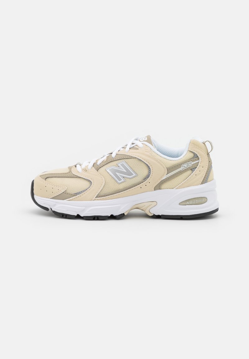 Baskets New Balance 530 beige avec lacets blancs, semelle blanche, dessus en mesh et cuir, et semelle extérieure noire, vues de profil gauche.