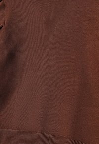 Braun gestrickter Stoff mit einer glatten Textur; verfügt über einen gerippten Saum am Boden, der ein enganliegendes Aussehen bietet.