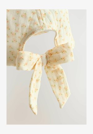 Akcesorium w kwiatowy wzór z miękkiego, żółtego materiału z kokardą z tyłu oraz otworem na głowę. Teksturowane i lekkie.
