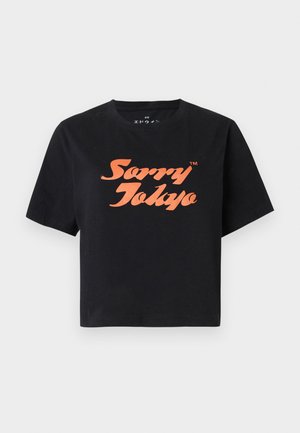 Camiseta negra de manga corta con texto "Sorry Tokyo" en naranja, con fuente estilizada, centrado en el frente.