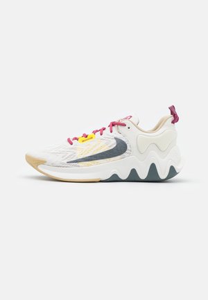 Chaussure de sport blanche avec semelle ondulée, logo swoosh gris, lacets roses et détail jaune sur les lacets, vue de profil sur un fond uni.