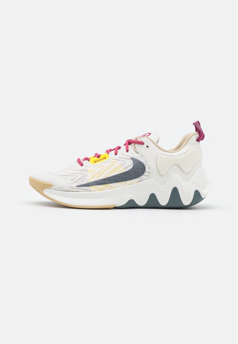 Chaussure de sport blanche avec semelle ondulée, logo swoosh gris, lacets roses et détail jaune sur les lacets, vue de profil sur un fond uni.