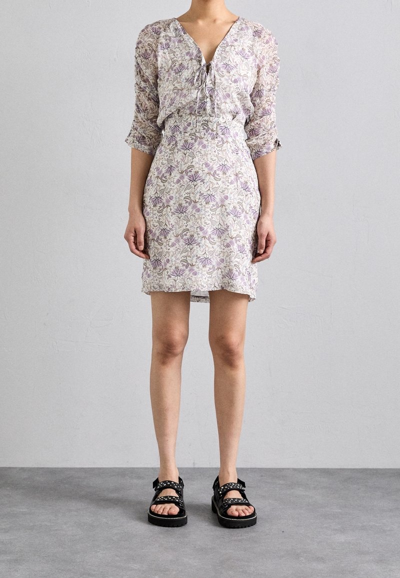 Floral dress with a V-neckline, long sleeves, and elastic waist; features lavender and green patterns. Black sandals with buckles.