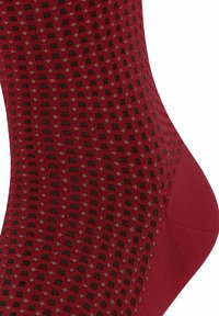 Rote Socken mit einem strukturierten Muster aus kleinen schwarzen Quadraten und grauen Punkten. Das Material ist glatt mit verstärktem Fersen- und Zehenbereich.