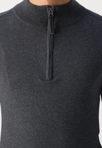 Maglione grigio scuro con zip e colletto alto, caratterizzato da un bordo a coste e un tessuto texturizzato. La zip si estende per metà sulla parte anteriore.