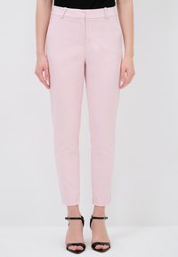 Lichtroze op maat gemaakte broek met een slim fit, met een platte voorkant, riemlussen en een enkellange zoom. Gecombineerd met zwarte bandjeshakken.