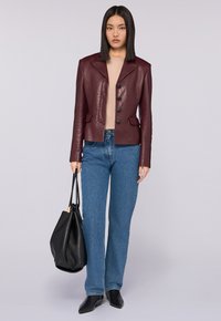 Bordowa skórzana kurtka o dopasowanym kroju, z klapami i czterema guzikami. Połączona z jasnoniebieskimi dżinsami i czarną torebką.