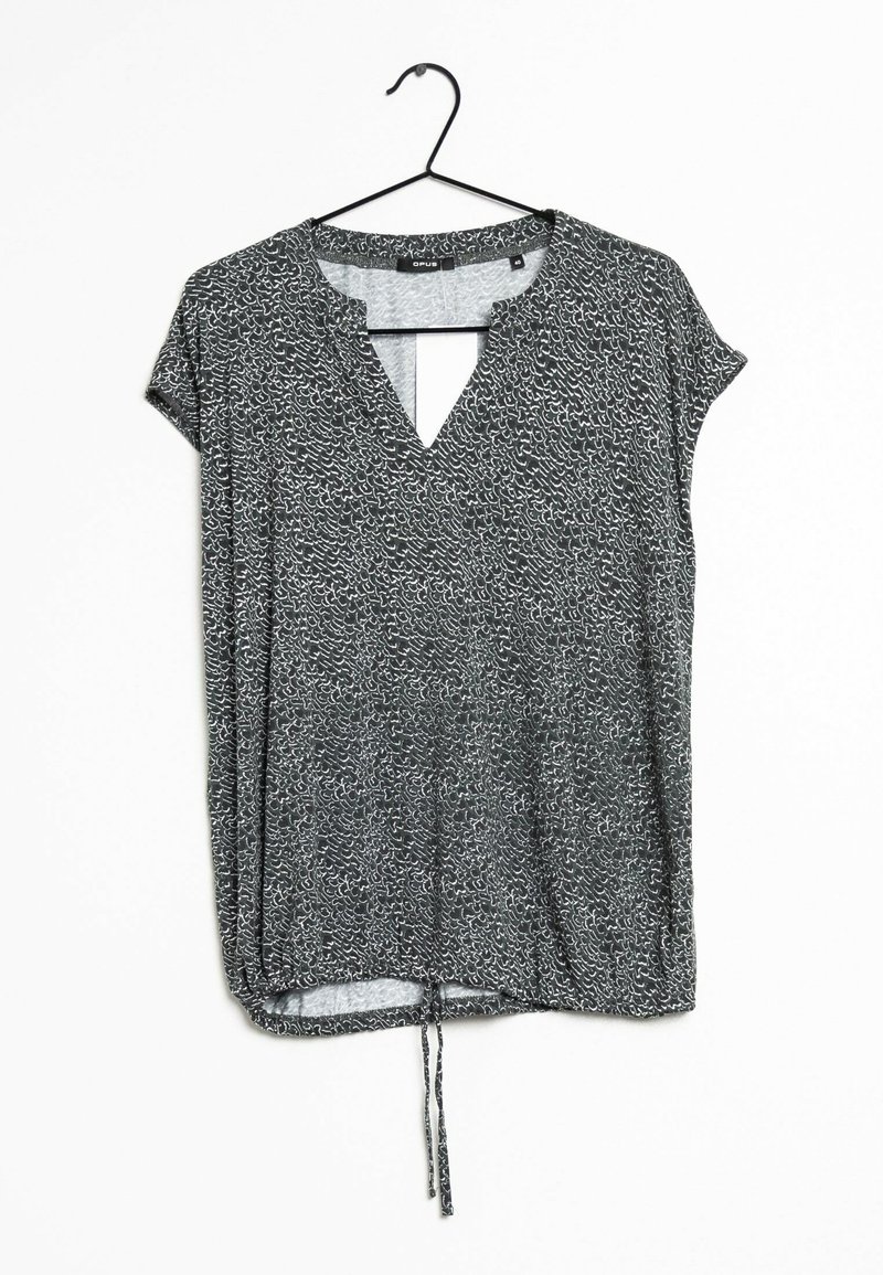 Blouse à manches courtes à motifs noir et blanc avec col en V et ourlet à cordon ajustable, suspendue sur un cintre noir sur fond blanc.