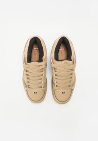 Tan sneakers with fabric upper, perforated toe box, and flat laces. Black inner lining and subtle logo detail on the side. Low-top design.
