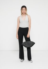 Gray sleeveless bodysuit, black high-waisted trousers, and a black handbag with elongated handles, displayed against a white background.