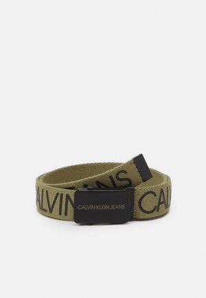 Ceinture en tissu vert olive avec boucle en métal noire, "CALVIN KLEIN JEANS" imprimé en noir sur le tissu et en or sur la boucle.
