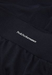 Shorts sportivi neri in tessuto testurizzato con vita elasticizzata, caratterizzati dal logo bianco "PeakPerformance" sul fronte.