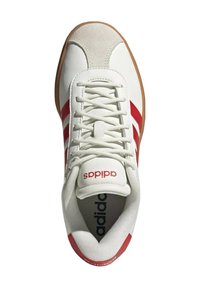 Sneaker bianco con accenti rossi, punta in suede, linguetta in mesh e lacci bianchi con texture. Suola in gomma con logo sulla linguetta e sul lato.