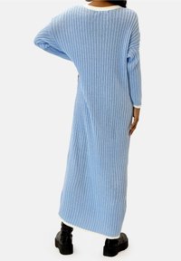 Robe longue bleu clair côtelée avec un large décolleté, des manches longues et une bordure couleur crème à l'ourlet et aux poignets. Confectionnée en maille douce.