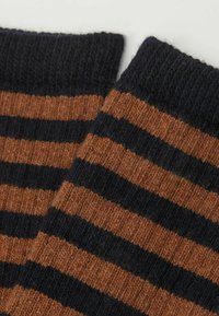 Stribede sokker i brun og mørkeblå med skiftende horisontale mønstre. Ribbet tekstur ved skaftet, lavet af strikket stof.