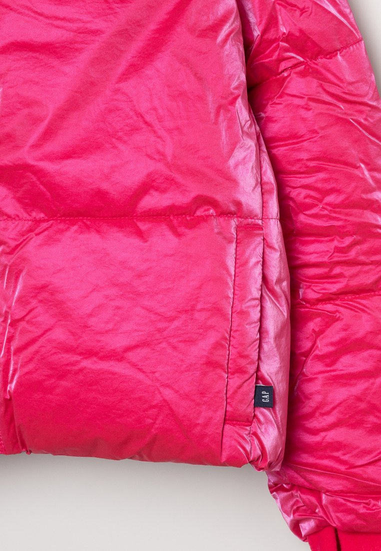 Veste rose gonflante en matériau synthétique brillant, dotée d'une poche zippée, d'une texture lisse et d'une étiquette logo discrète.