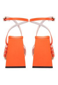 Sandali con tacco alto arancioni, dotati di un spesso tacco quadrato e cinturini bianchi alla caviglia, caratterizzati da un design incrociato sulle dita dei piedi.